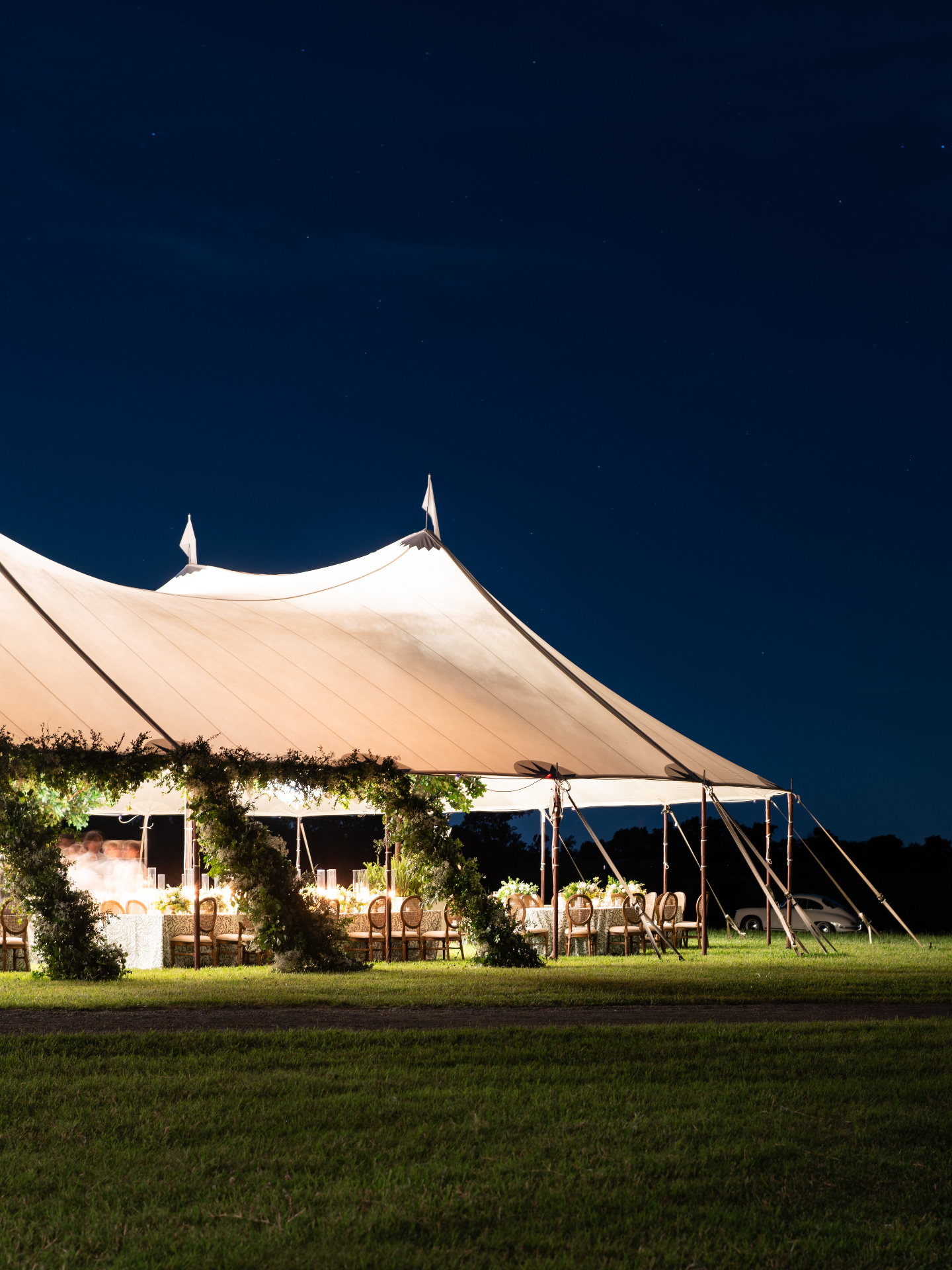 Sailcloth pavilion at night with guests gathered at Augustus Hill