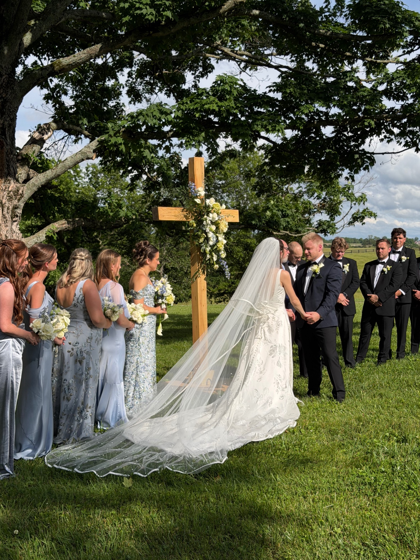 A bride and groom exchanging vows beneath a wooden cross at Augustus Hill Farm